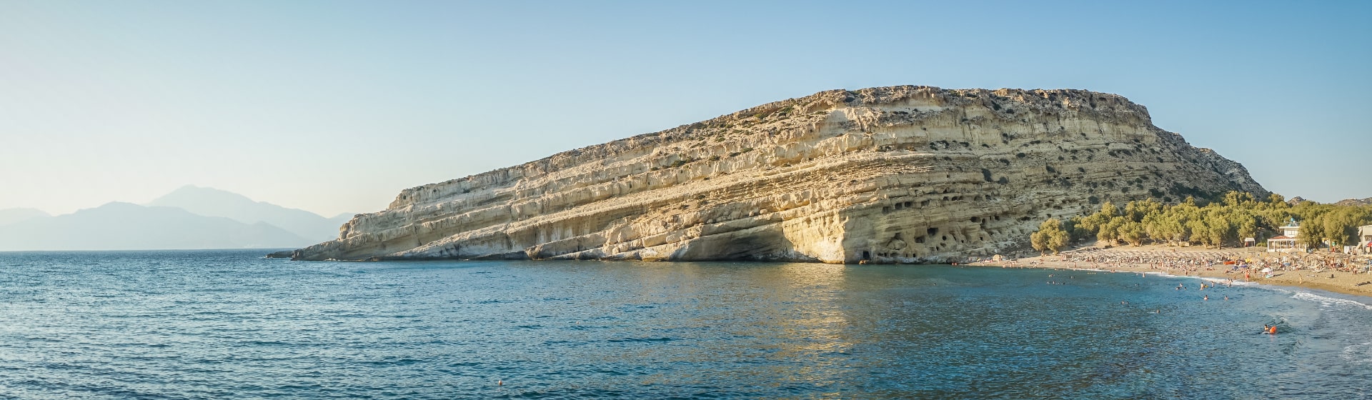 Klif z wykutymi jaskiniami, morze i kawałek plaży